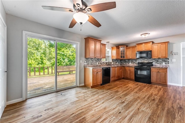 kitchen with black appliances, tasteful backsplash, light wood-type flooring, and a sink