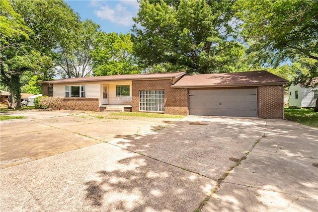 single story home with driveway, an attached garage, and brick siding