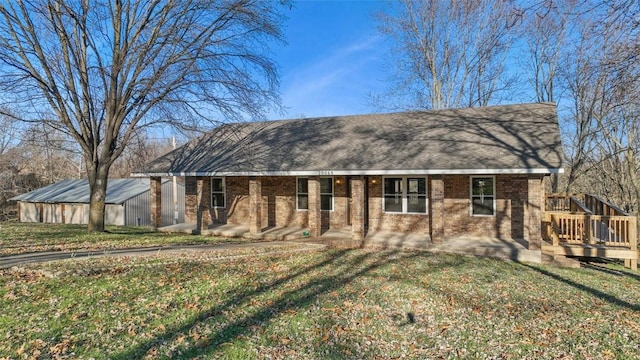 view of front of property featuring a front yard, brick siding, and roof with shingles