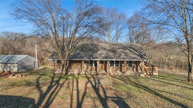 exterior space with dirt driveway, a yard, brick siding, and an outbuilding