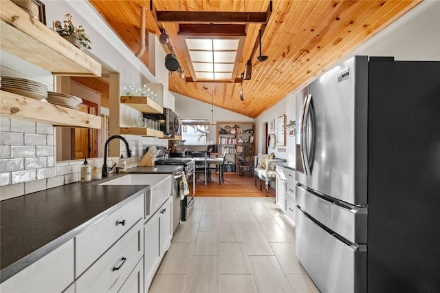 kitchen featuring open shelves, a sink, appliances with stainless steel finishes, white cabinetry, and dark countertops