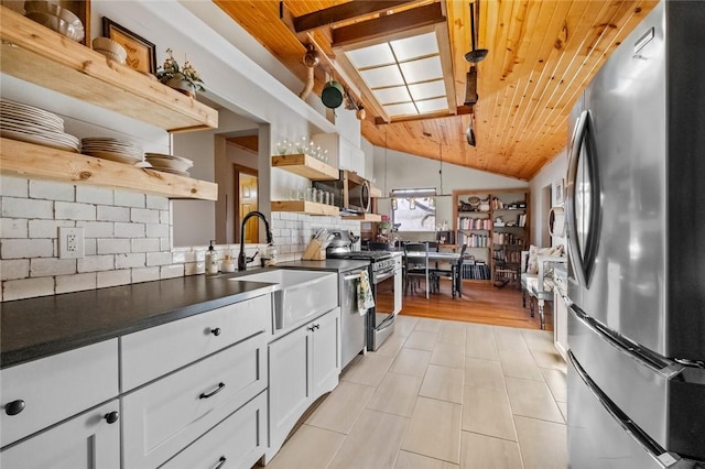 kitchen with dark countertops, open shelves, appliances with stainless steel finishes, white cabinets, and a sink