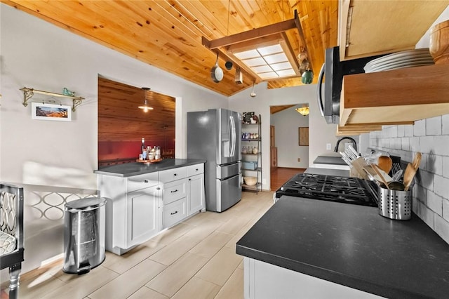 kitchen featuring dark countertops, range with gas cooktop, stainless steel fridge, white cabinets, and wood ceiling