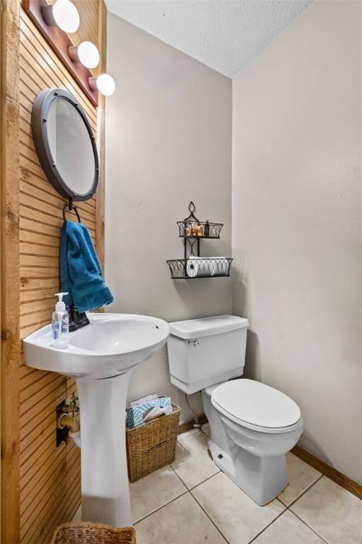 bathroom with tile patterned flooring, toilet, baseboards, and a textured ceiling