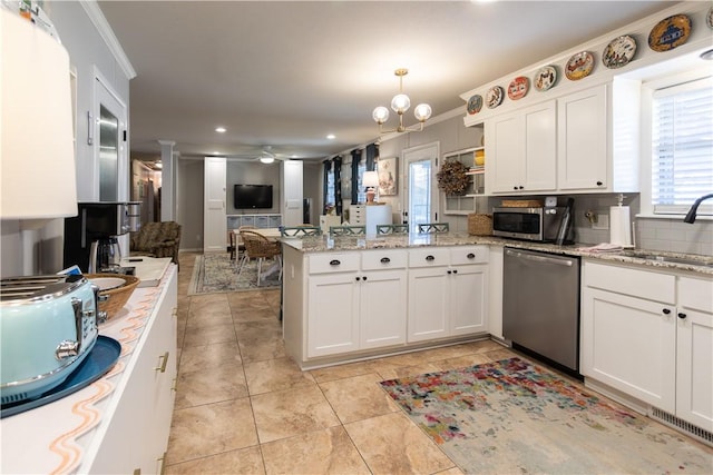 kitchen with a sink, stainless steel appliances, a peninsula, white cabinets, and crown molding