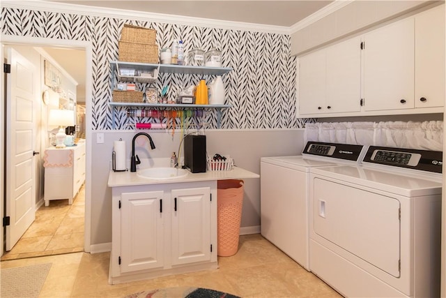 washroom featuring wallpapered walls, crown molding, washing machine and dryer, cabinet space, and a sink