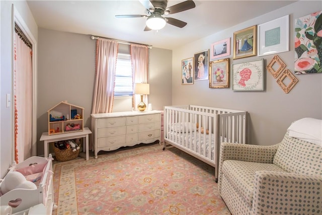 bedroom featuring a nursery area, a closet, and ceiling fan