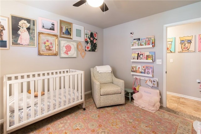 bedroom featuring a nursery area, a ceiling fan, and baseboards