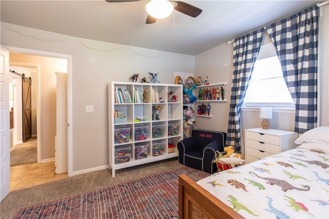 carpeted bedroom featuring a ceiling fan and a barn door