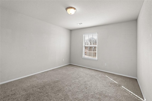 carpeted empty room featuring baseboards and a textured ceiling