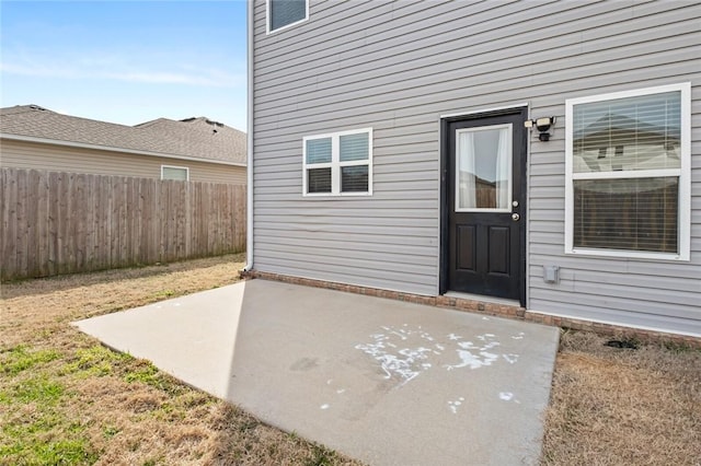 view of exterior entry with a patio and fence