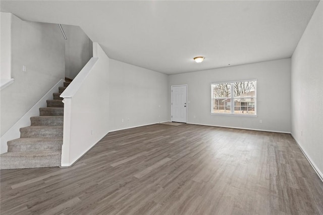 unfurnished living room with stairs and wood finished floors