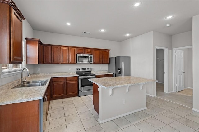 kitchen with a breakfast bar, a kitchen island, visible vents, appliances with stainless steel finishes, and a sink