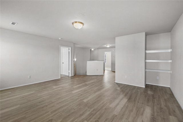 interior space featuring wood finished floors, baseboards, and visible vents