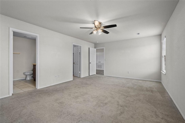 unfurnished bedroom featuring ceiling fan, baseboards, connected bathroom, and carpet floors