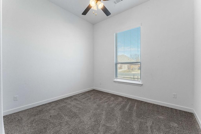 spare room featuring baseboards, visible vents, dark carpet, and a ceiling fan