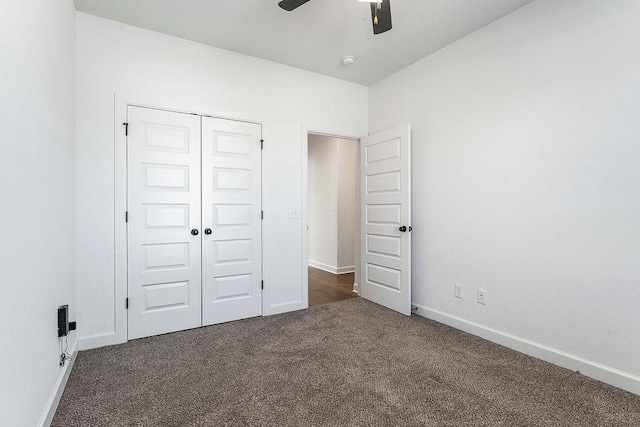 unfurnished bedroom with a ceiling fan, baseboards, dark colored carpet, and a closet