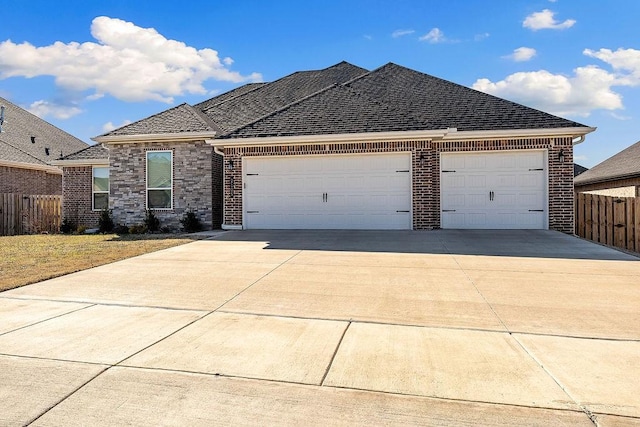 view of front of home with a shingled roof, concrete driveway, an attached garage, fence, and brick siding