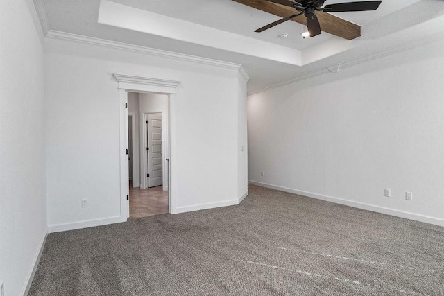 carpeted spare room with baseboards, a tray ceiling, and ornamental molding