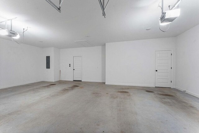 garage with a garage door opener, electric panel, and baseboards