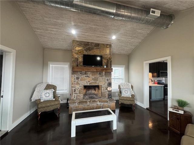 living room with concrete flooring, vaulted ceiling, a stone fireplace, and baseboards