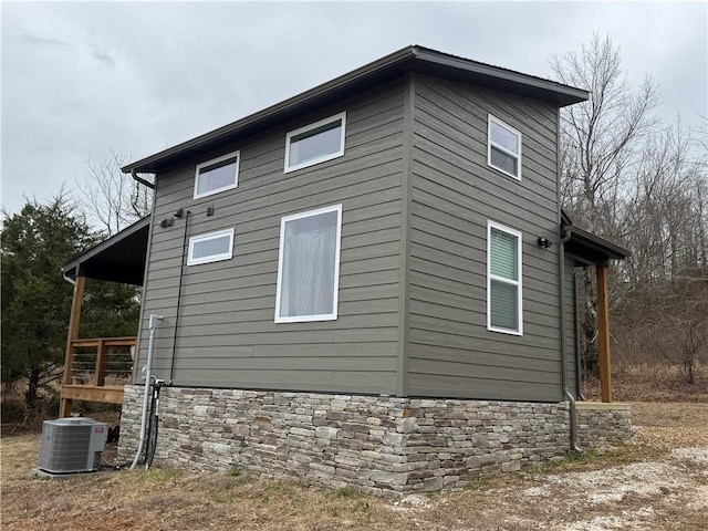 view of side of property featuring stone siding and central AC