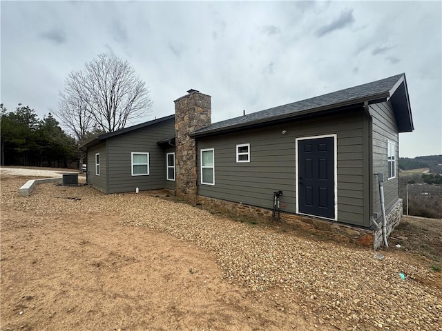 rear view of house featuring a chimney and cooling unit