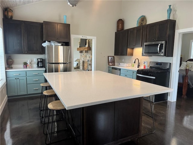 kitchen featuring stainless steel appliances, a center island, light countertops, and a kitchen bar