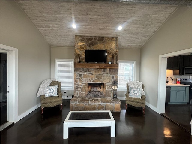 living room with finished concrete floors, a fireplace, baseboards, and vaulted ceiling