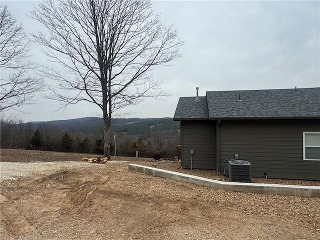 view of property exterior featuring central AC unit and a shingled roof