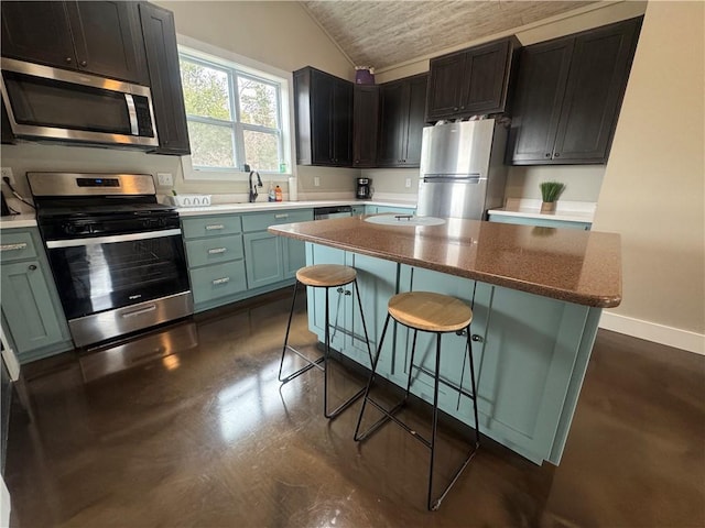 kitchen with a breakfast bar, lofted ceiling, appliances with stainless steel finishes, a kitchen island, and baseboards