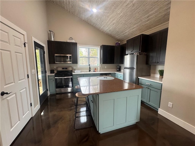 kitchen featuring baseboards, lofted ceiling, a kitchen island, stainless steel appliances, and a sink