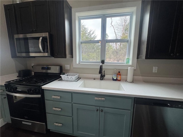 kitchen with appliances with stainless steel finishes, light countertops, and a sink