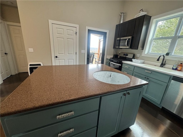 kitchen featuring appliances with stainless steel finishes, dark wood-type flooring, a sink, and a center island