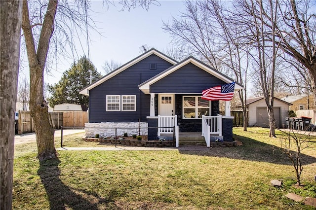 view of front of property with a detached garage, covered porch, fence, an outdoor structure, and a front lawn