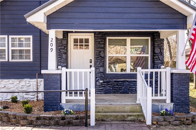 entrance to property featuring stone siding and covered porch