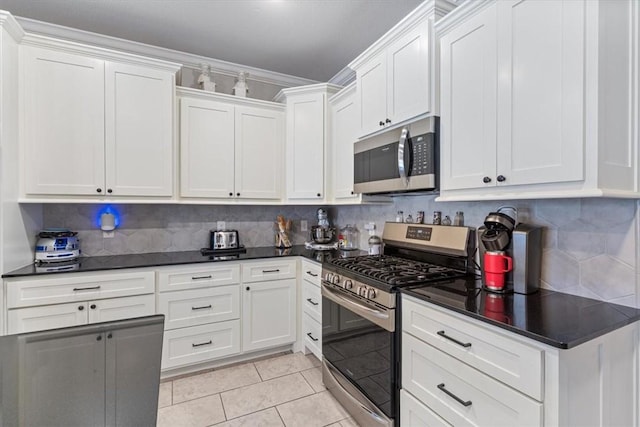 kitchen with light tile patterned floors, dark countertops, backsplash, appliances with stainless steel finishes, and white cabinets