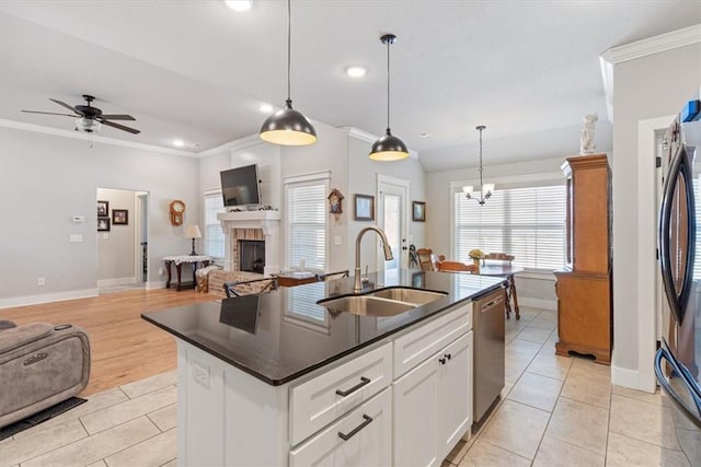 kitchen featuring dark countertops, open floor plan, stainless steel appliances, a fireplace, and a sink