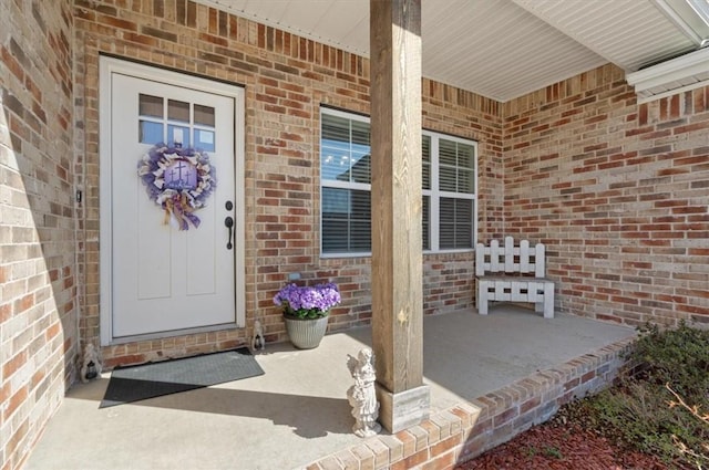 property entrance featuring covered porch and brick siding