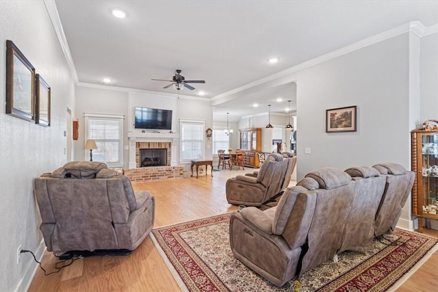 living room with ceiling fan, recessed lighting, a fireplace, light wood-style floors, and ornamental molding