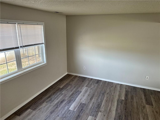 spare room with dark wood finished floors, a textured ceiling, and baseboards