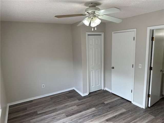 unfurnished bedroom with dark wood finished floors, a closet, ceiling fan, a textured ceiling, and baseboards