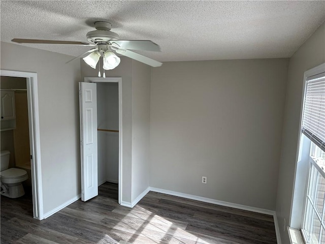 unfurnished bedroom featuring ceiling fan, a textured ceiling, baseboards, a closet, and dark wood-style floors