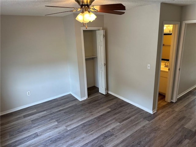 unfurnished bedroom featuring a textured ceiling, a closet, dark wood finished floors, and baseboards