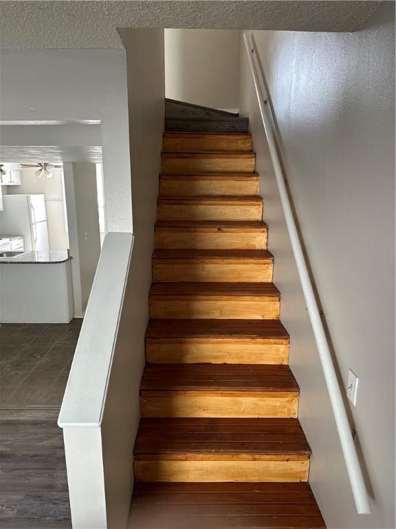 stairs with a textured ceiling and wood finished floors