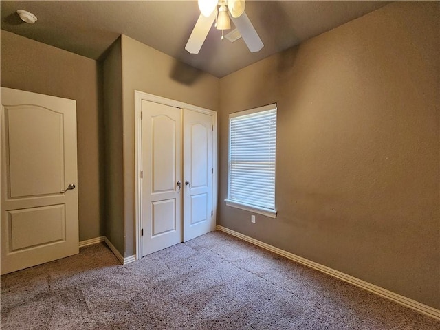 unfurnished bedroom with ceiling fan, a closet, carpet flooring, and baseboards