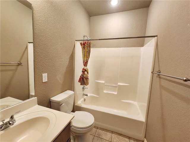 bathroom with a textured wall, toilet, tile patterned flooring, vanity, and washtub / shower combination