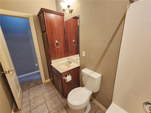 half bath featuring baseboards, a textured wall, toilet, tile patterned floors, and vanity