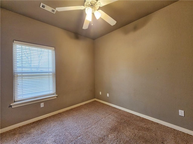 carpeted spare room with a ceiling fan, visible vents, and baseboards