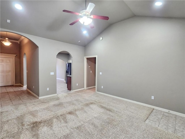 tiled empty room featuring arched walkways, lofted ceiling, carpet floors, a ceiling fan, and baseboards